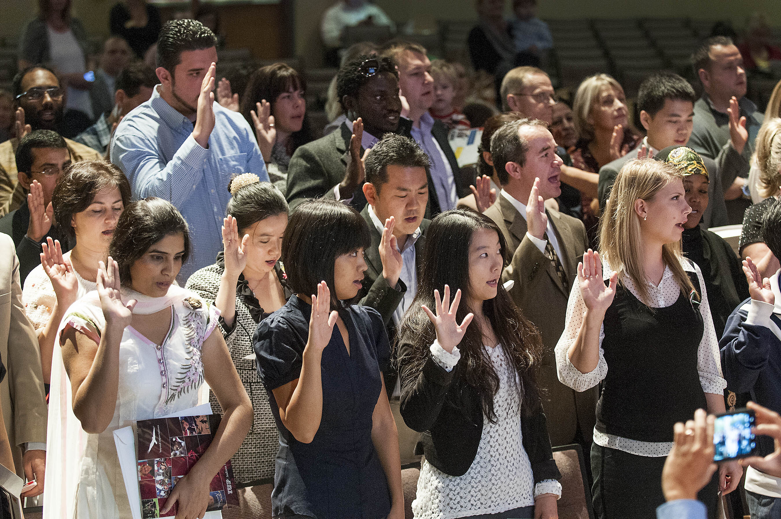 A group of people stand during a citizenship naturalization program
