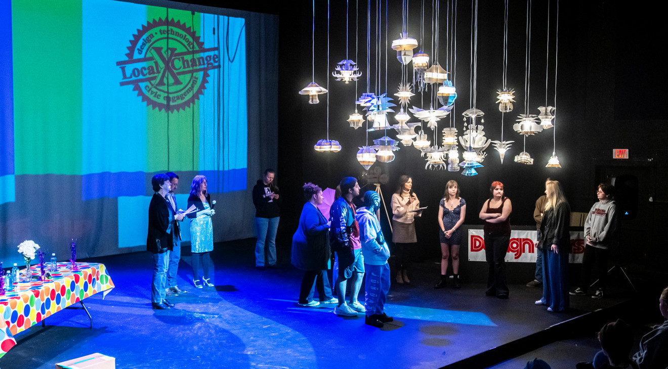 studets standing on stage with various hanging lamps above them