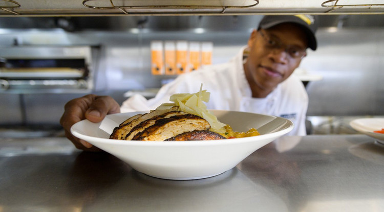 Arnold Ivey placing a finished dish on a metal table