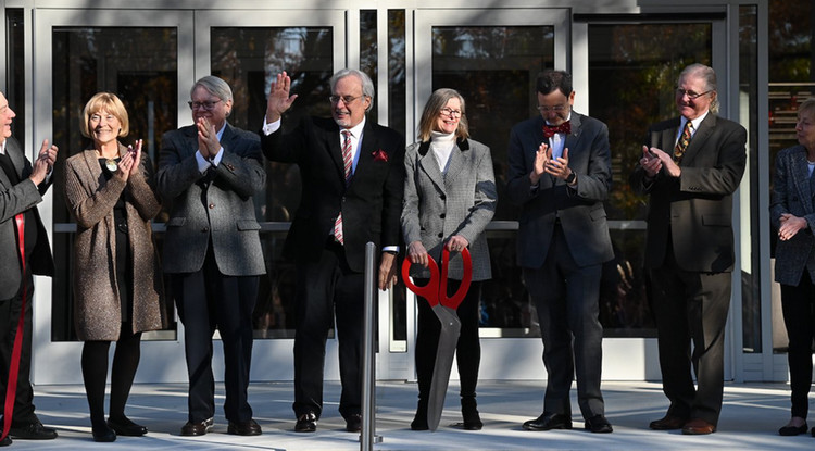 a group of people standing in front of a building cutting a ribbon