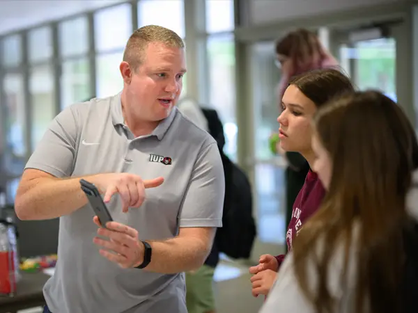 Jeremy Risinger showing students information on a smartphone.