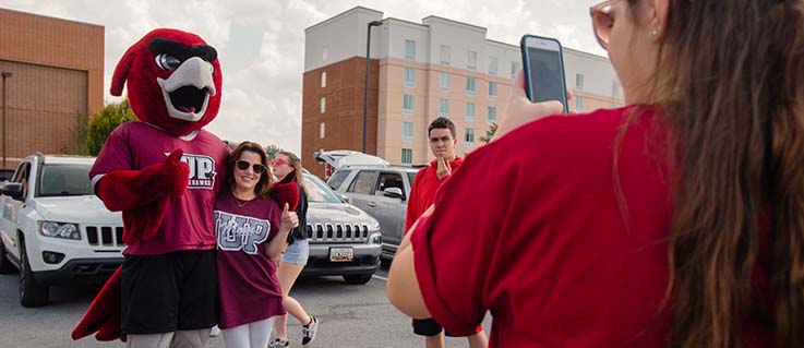 IUP student poses with Norm while her parent takes a photo. 