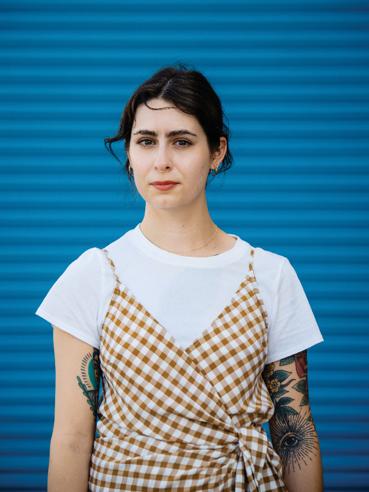 Portrait of Taylor Jones standing in front of a blue background with horizontal ridges