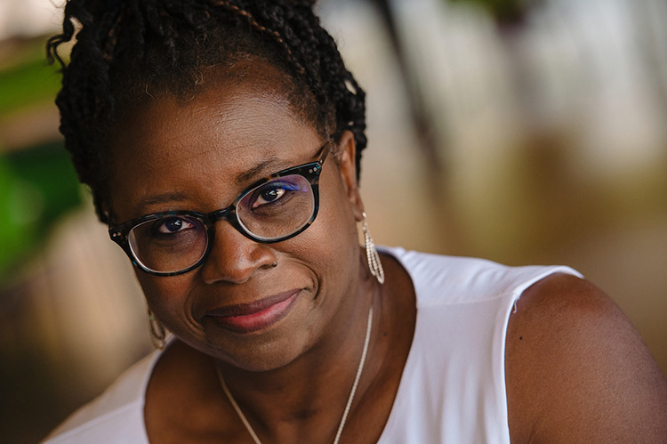 Veronica Watson, wearing a white shirt and cross necklace, waits to be interviewed.