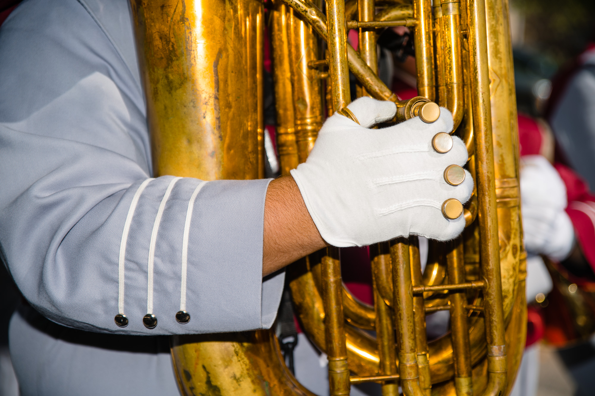 A detail photograph of a tuba player holding their instrument.