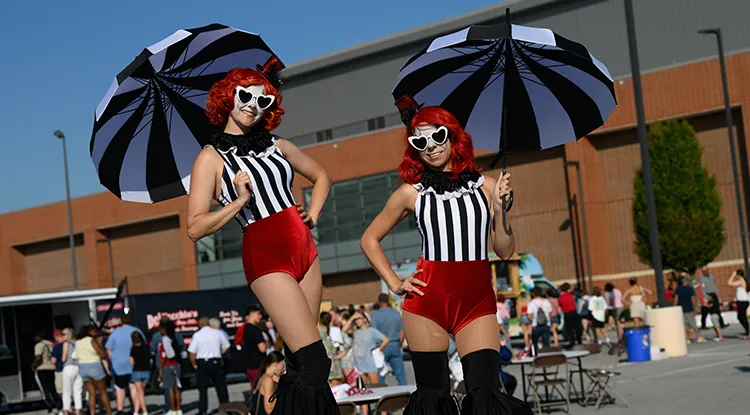 Performers on stilts holding umbrellas pose for the camera