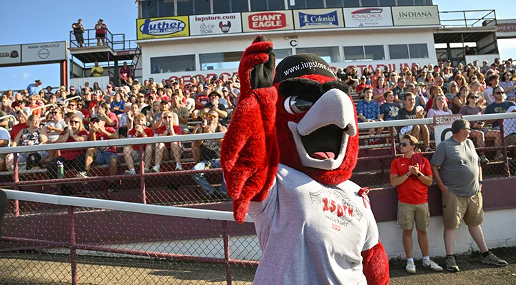 IUP mascot Norm waving in front of a crowd of sitting in bleachers