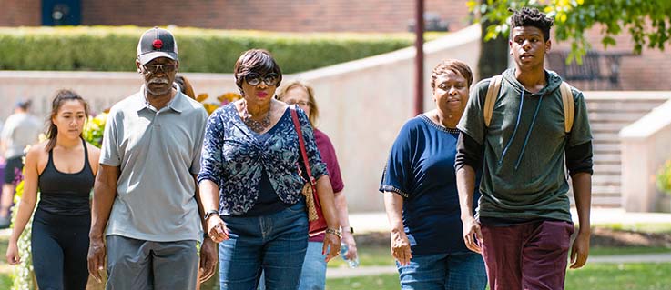 IUP students and families walk through the oak grove during family weekend.