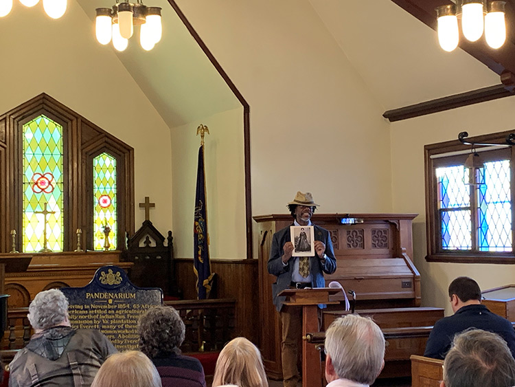 Roland Barksdale-Hall held up a photo as he spoke from a church podium with the plaque from the Pandenarium historical marker displayed in front of him.