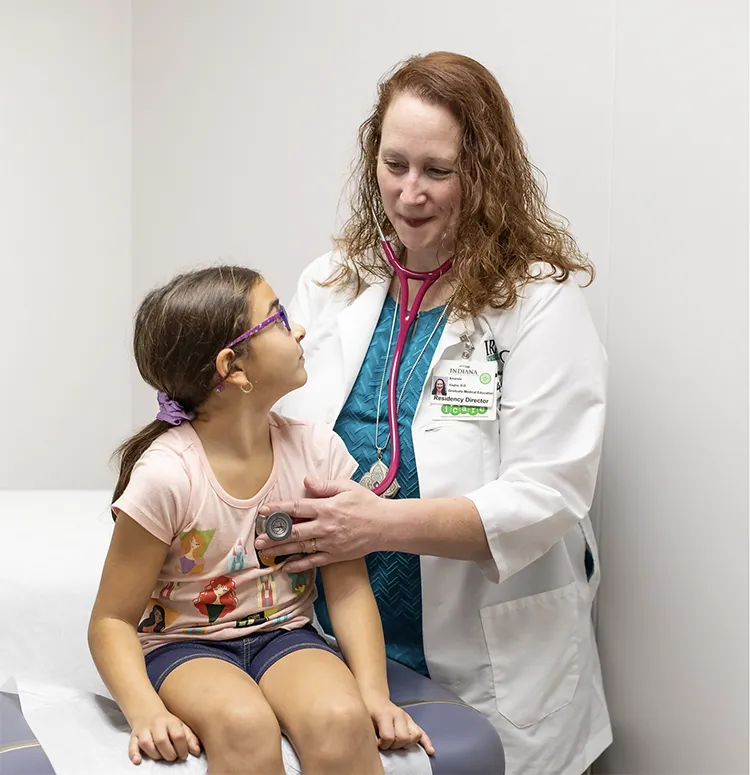 a doctor uses a stethoscope to check the heartbeat of a young girl