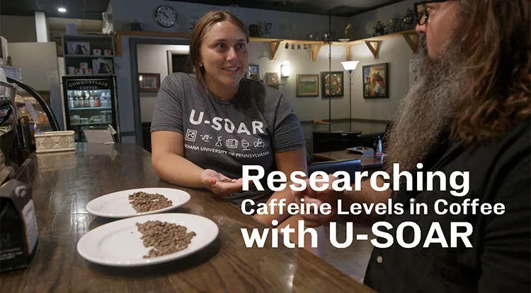 a student sitting and talking to a person while two plates of coffee beans rest on the countertop