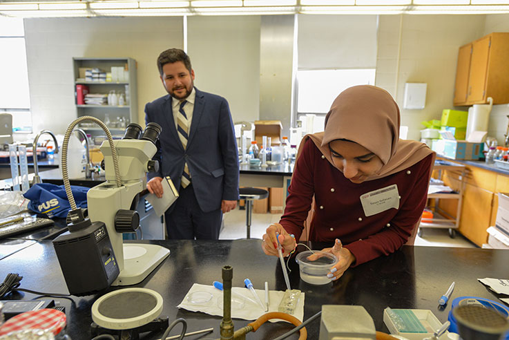Eric Hagarty watching Eman Soliman, a student in the U-SOAR program, work in the lab.
