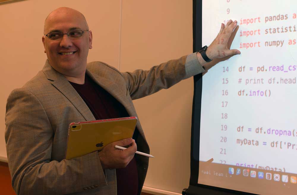 Presenter at a conference pointing to code on a projector screen