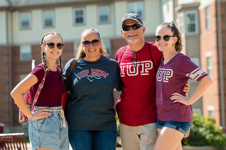 A family posing outside of a residence hall during Parent and Family Weekend.