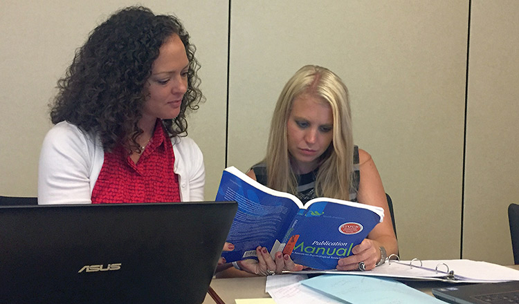 A professor and student study a textbook in Professional Studies in Education