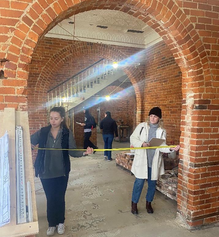 Interior design students measuring an arched doorway