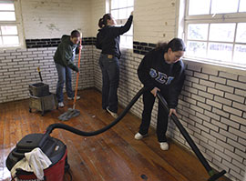 Students clean a building as part of community-service work.
