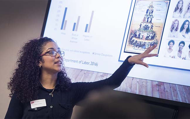 a woman presenting information projected on a white screen