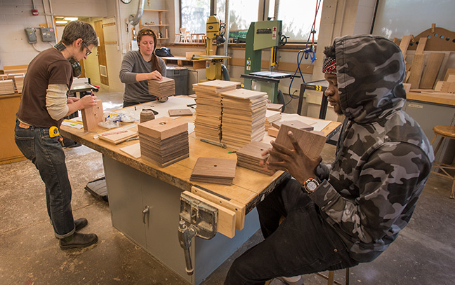 Students work with a professor in the wood center