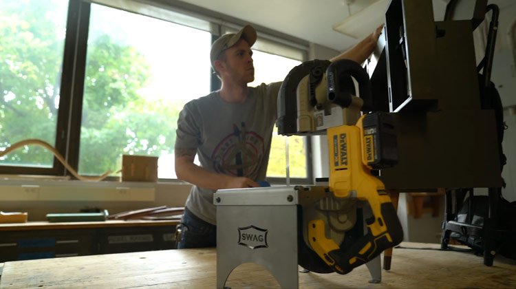 Tyler Stanton at a table using woodworking equipment