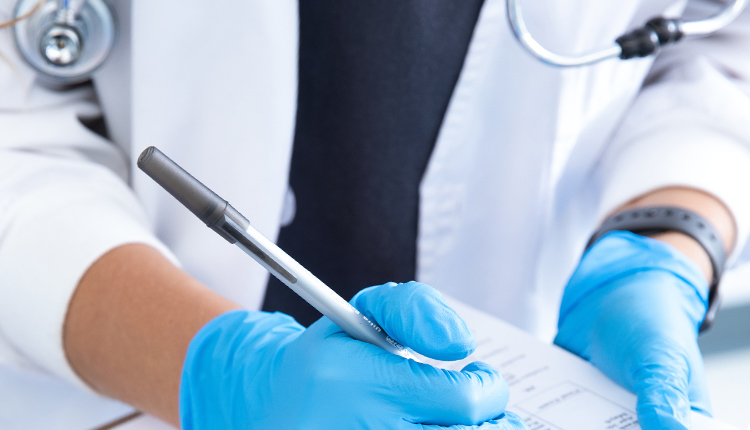 Hands of a medical technician wearing medical gloves and holding a clipboard