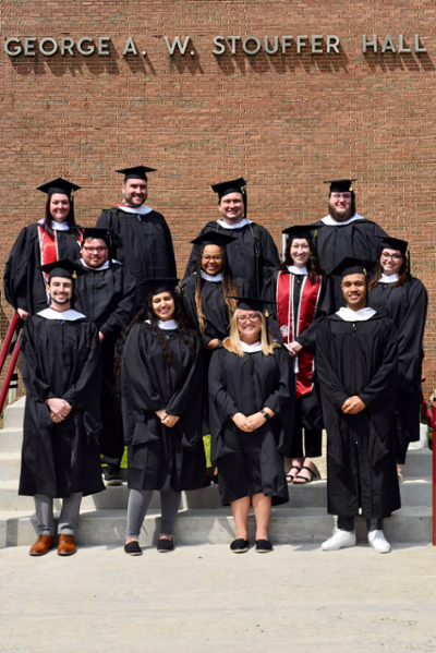 Group of 12 students in academic regalia. 