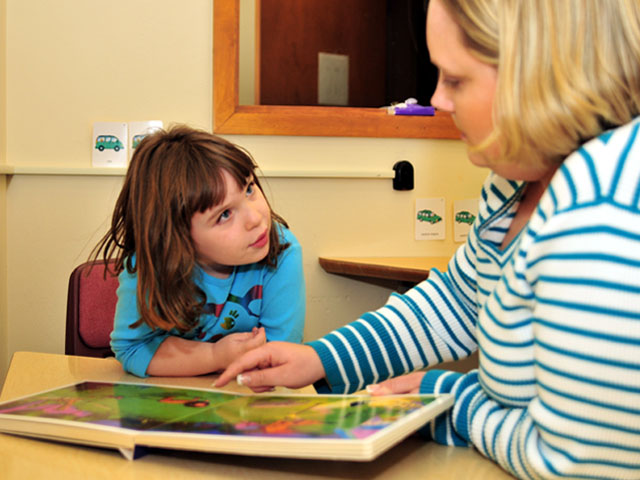 A staff member helping a child discuss a book