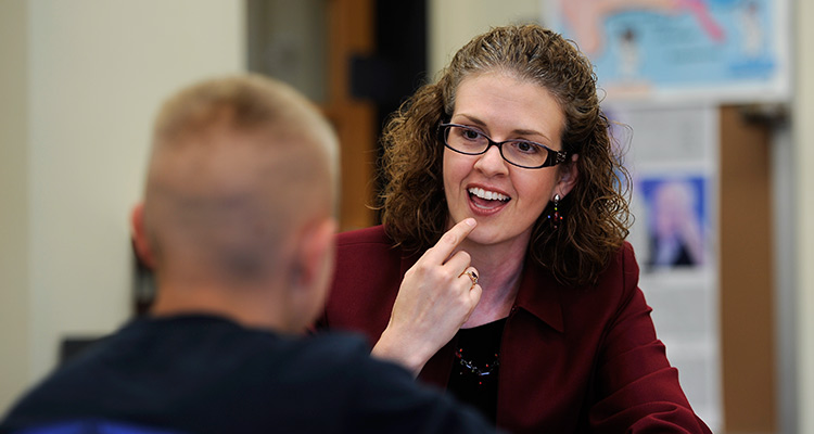 A teacher instructs a young student how to use his voice properly.