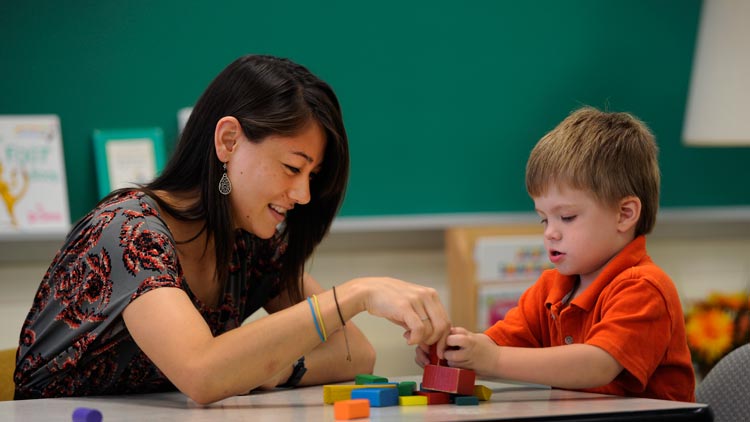 A teacher and child build with blocks together