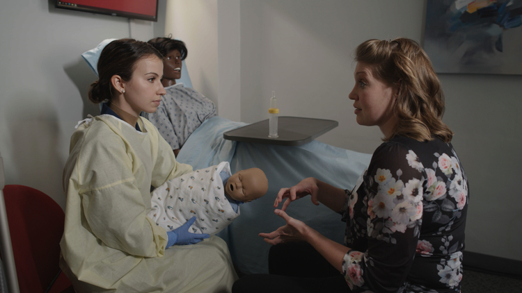 Faculty instructing a student on infant feeding techniques