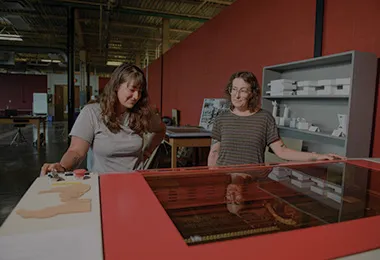 Two people standing in front of a large piece of equipment.