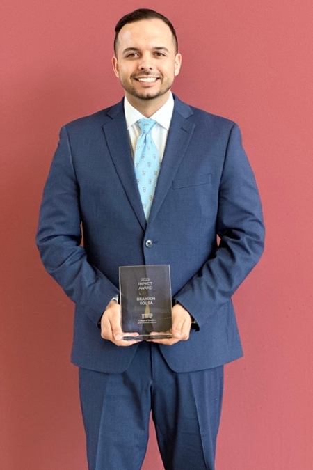 Brandon Sousa holding Impact award.