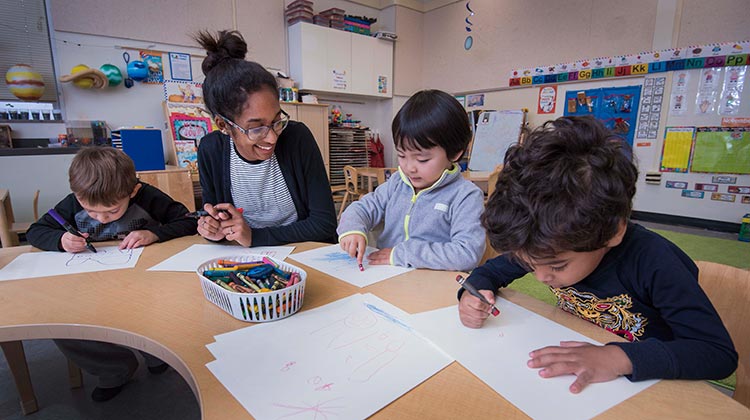 Student teacher with three young students who are coloring