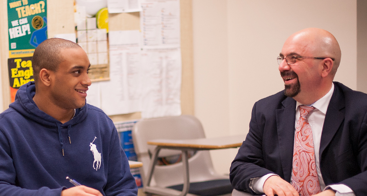 Student and professor talk in a classroom