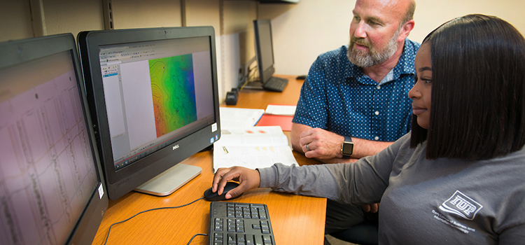 A student works with a Geoscience professor at a computer.