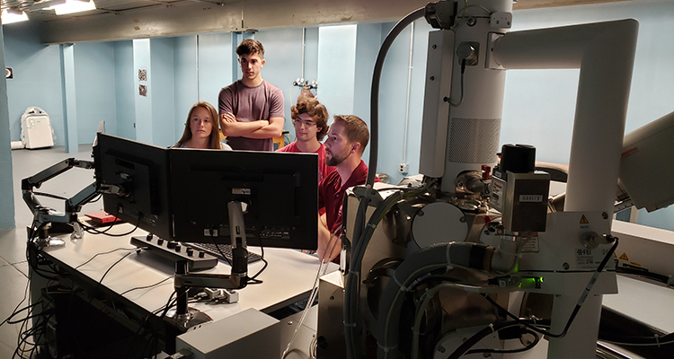 A group of four students work in a lab with high-tech equipment.