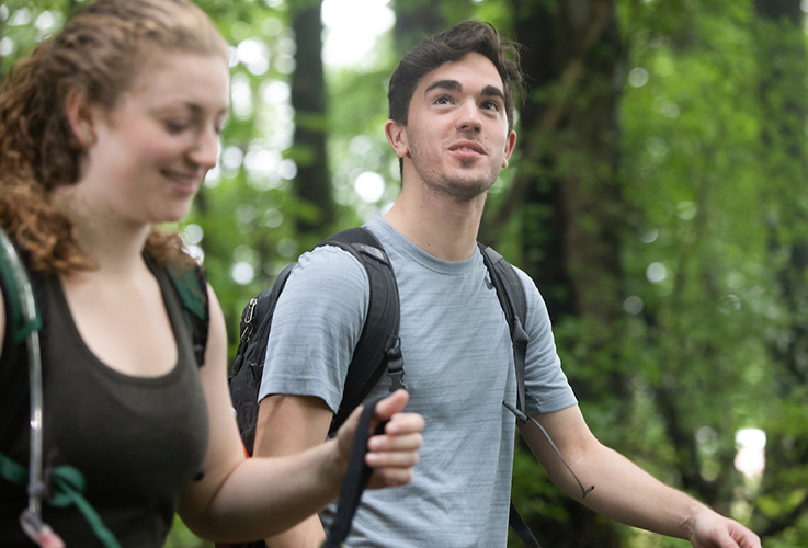 Two students hike in the woods at the IUP College Lodge.