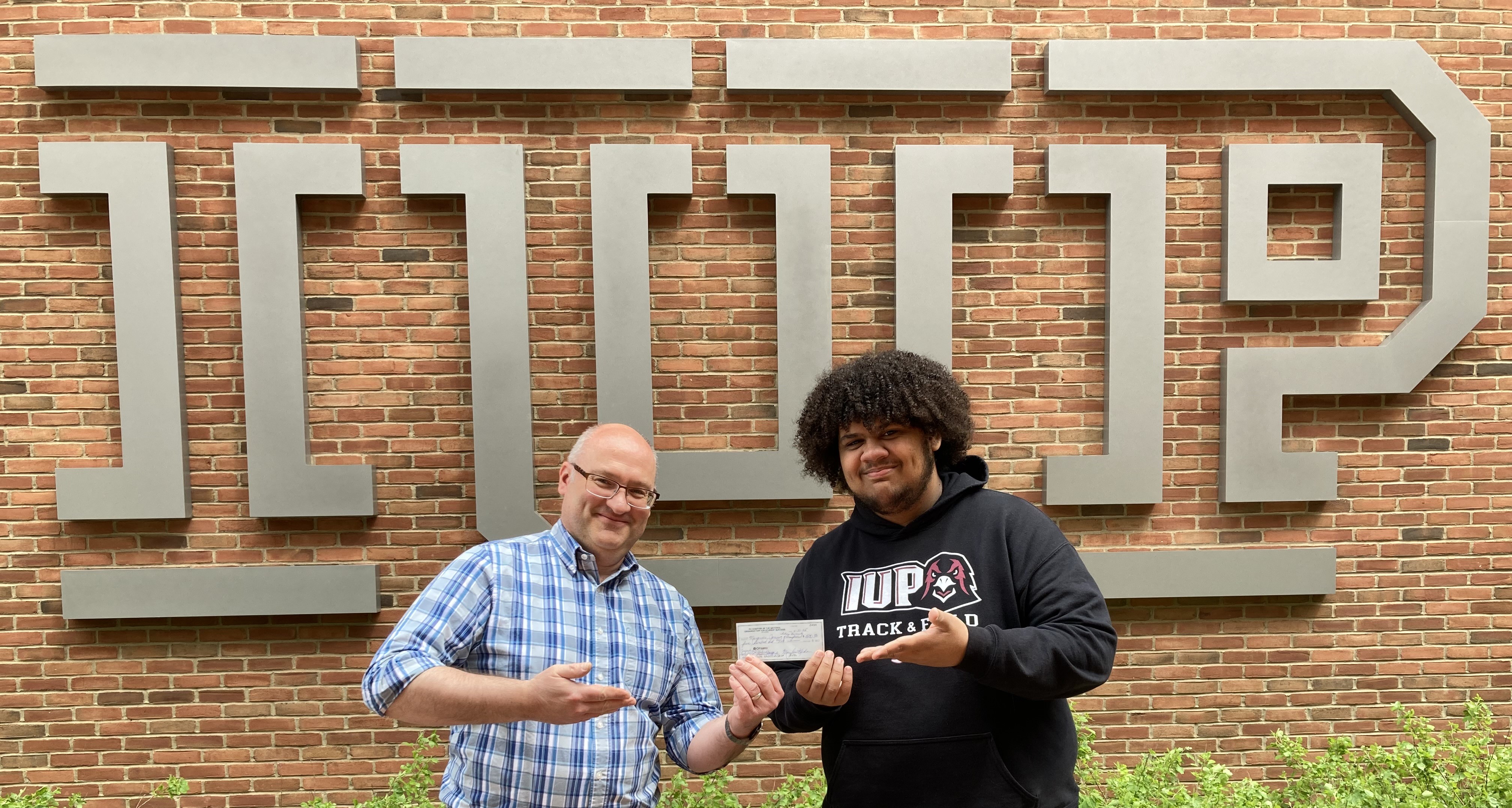 Marquice Jones (right) receives PA-NOSS check from University College staff member Stephan Schaffrath