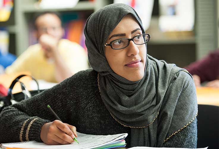 A student takes notes in a classroom