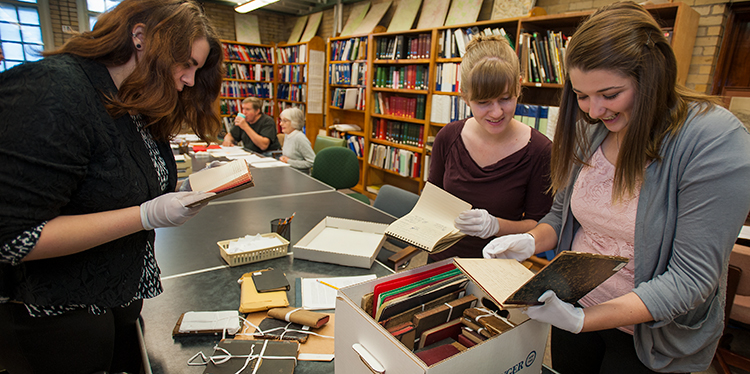 Student look through old records at the Historical Society, about a block from campus.