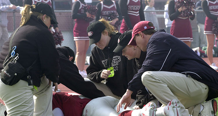 IUP Athletic trainers assess a football player lying prone on the field
