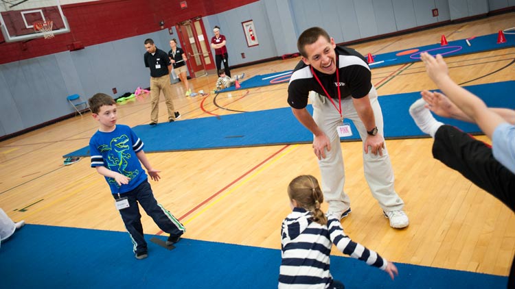 Kinesiology students working with children in a gym