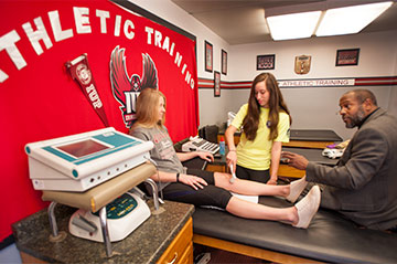 Kinesiology professor instructs students in an athletic training class Kinesiology professor instructs students in an athletic training class
