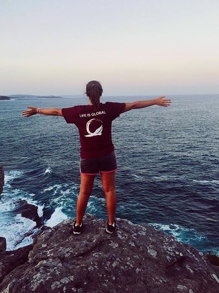 IUP student looking out over water with arms extended