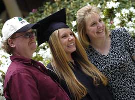 Student posing with parents after Commencement ceremony