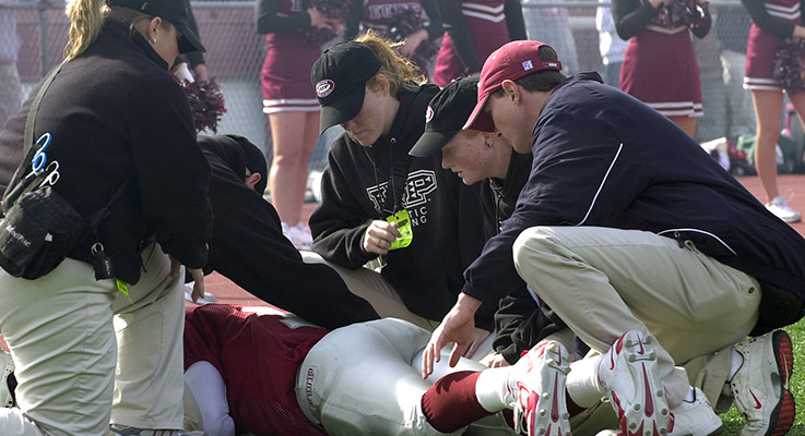 A group of student trainers assist an injured football player during an IUP game
