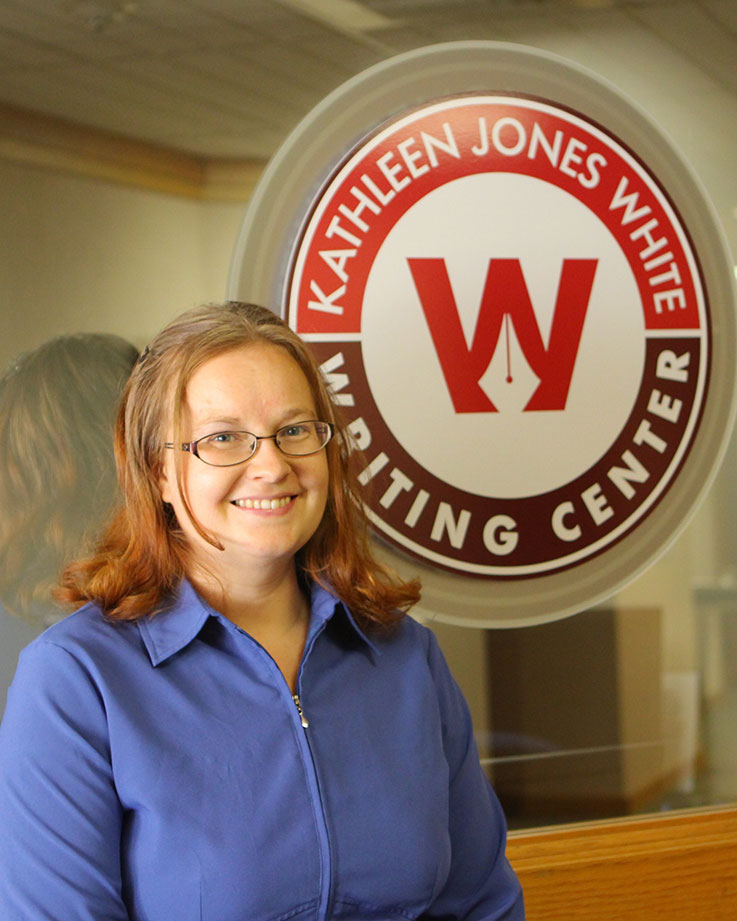 A woman standing beside the Jones White Writing Center logo 