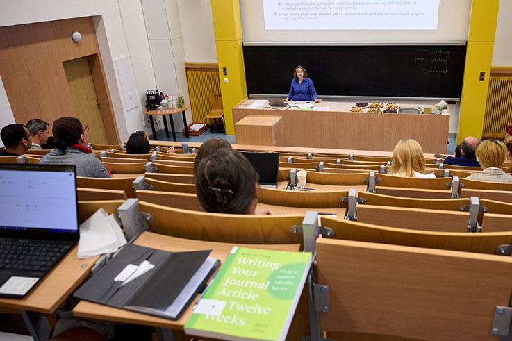 A woman leads a lecture to a classroom