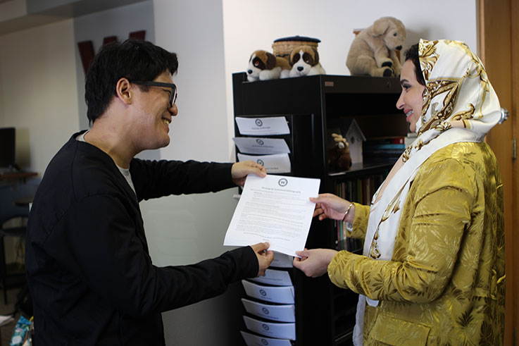 A male student gives a document to a female student